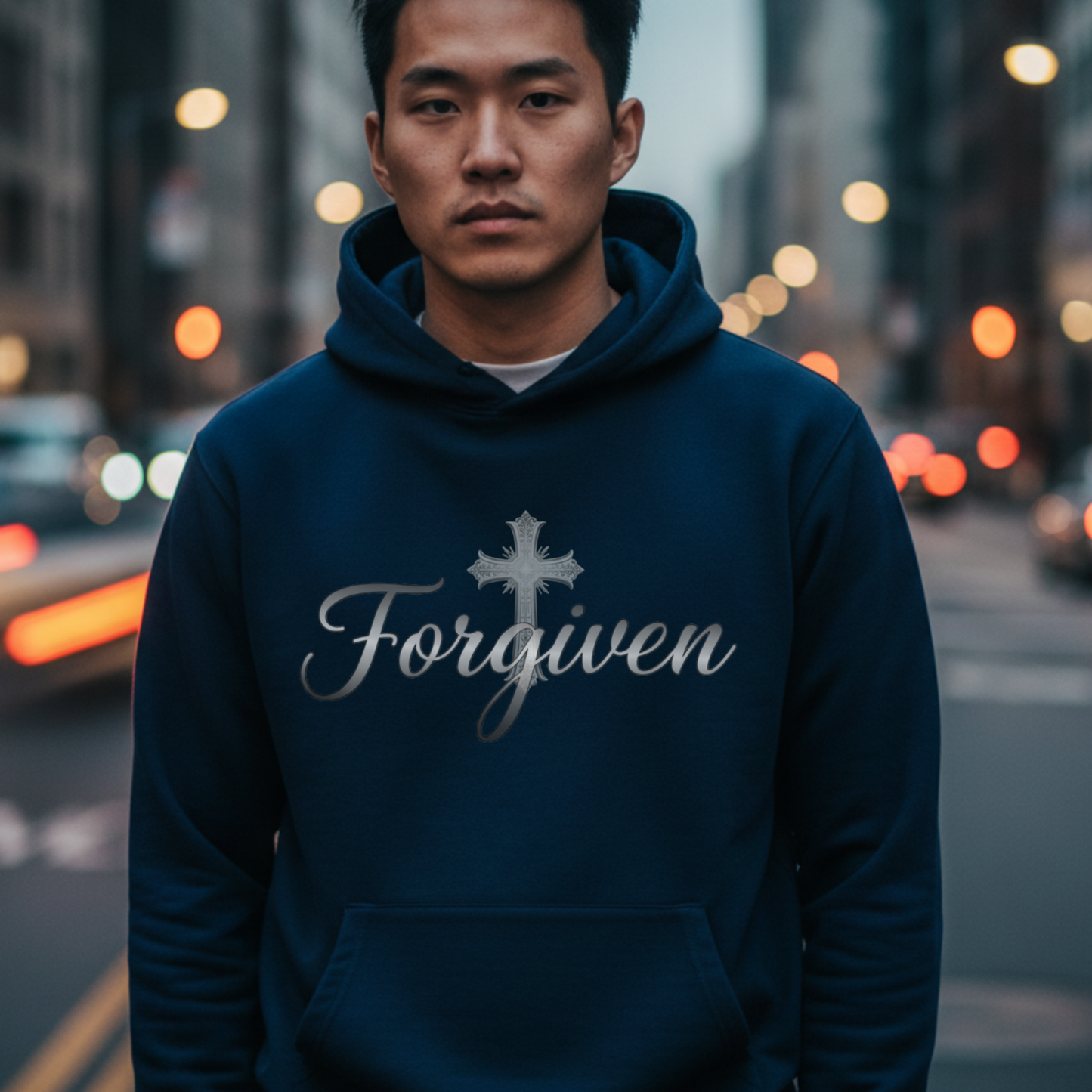 Man wearing a blue hoodie with 'Forgiven' text on a city street.