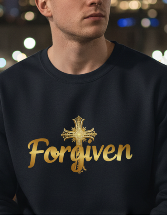Man wearing a sweatshirt with 'Forgiven' text sitting on a bench in a city at night.