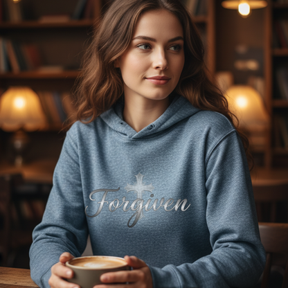 Woman wearing a blue hoodie with 'Forgiven' text, holding a cup in a cozy library setting.