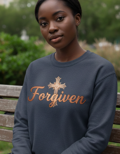Person wearing a sweatshirt with 'Forgiven' and a cross design, sitting on a bench outdoors.