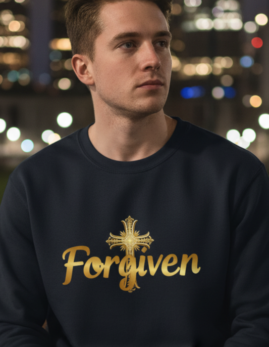Man wearing a sweatshirt with 'Forgiven' text sitting on a bench in a city at night.
