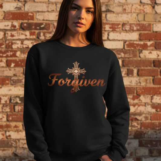 Woman wearing a black sweatshirt with 'Forgiven' text against a brick wall.