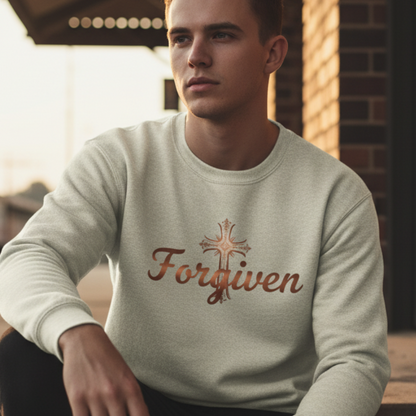 Man wearing a light green sweatshirt with 'Forgiven' and a cross design, sitting on steps.